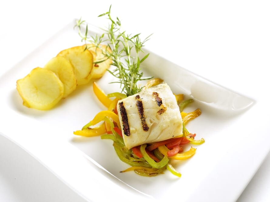 Lombo de Bacalhau grelhado sobre rodelas de batata e pimentos salteados